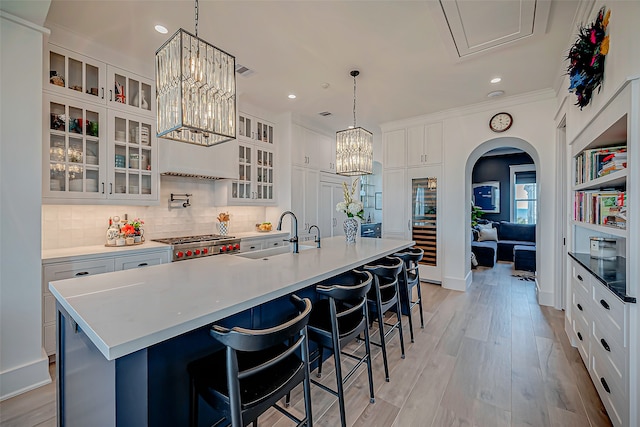 kitchen with white cabinets, light hardwood / wood-style flooring, a large island, and sink