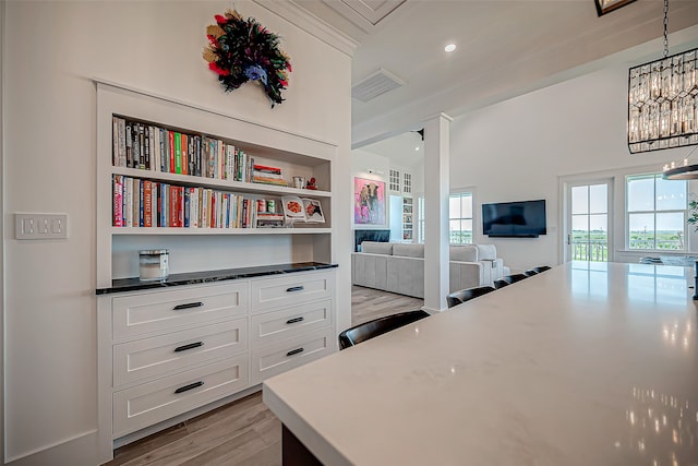 interior space featuring light wood-type flooring, crown molding, and a notable chandelier