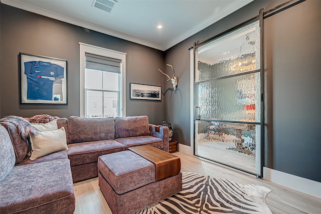 living room featuring light wood-type flooring, a barn door, and crown molding