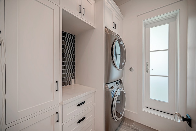 laundry room featuring cabinets, light wood-type flooring, and stacked washer / dryer