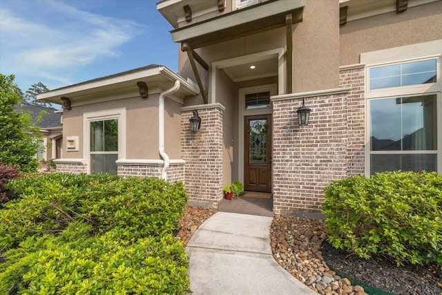 entrance to property featuring brick siding and stucco siding