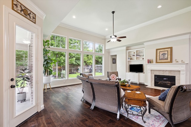 living room featuring ceiling fan, ornamental molding, a fireplace, and dark wood-type flooring