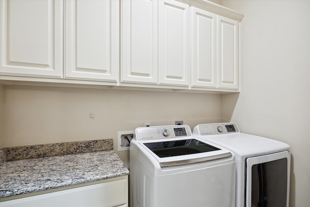 laundry room with washing machine and clothes dryer and cabinets