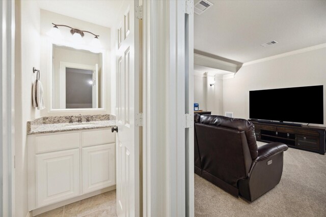 cinema room with light carpet, visible vents, a sink, and crown molding