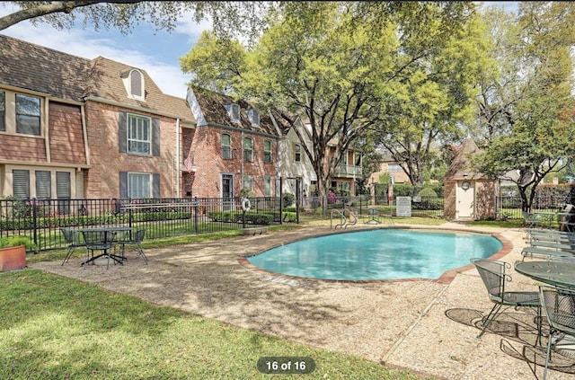 view of pool with a patio, a storage shed, and a lawn