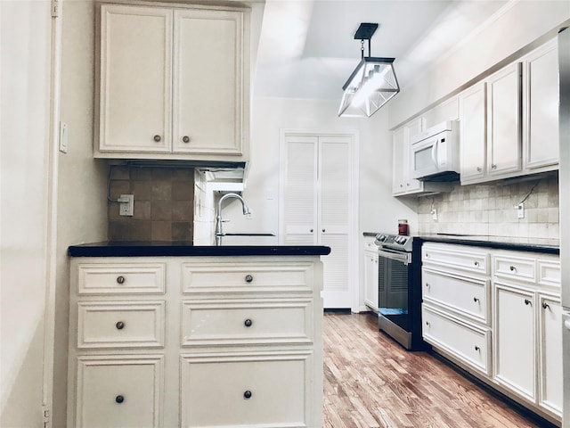 kitchen featuring stainless steel electric range oven, sink, hanging light fixtures, and backsplash