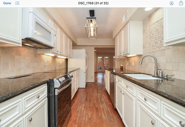 kitchen featuring stainless steel appliances, sink, dark stone counters, and white cabinets