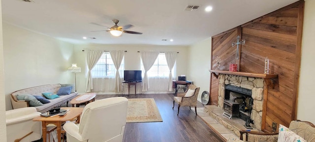 living room with ceiling fan, a stone fireplace, and dark hardwood / wood-style floors