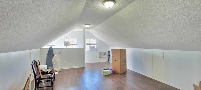 additional living space featuring a textured ceiling, lofted ceiling, and dark hardwood / wood-style flooring