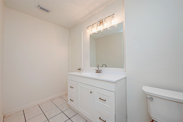 bathroom with vanity, toilet, a textured ceiling, and tile patterned flooring