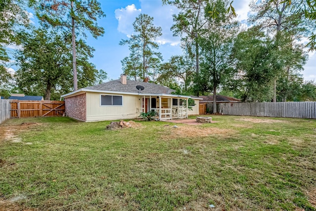 rear view of property with a yard, an outdoor fire pit, and a patio area