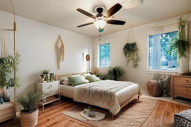 bedroom with ceiling fan, hardwood / wood-style flooring, and a textured ceiling