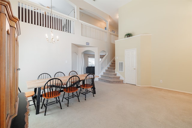 carpeted dining area with a high ceiling and an inviting chandelier