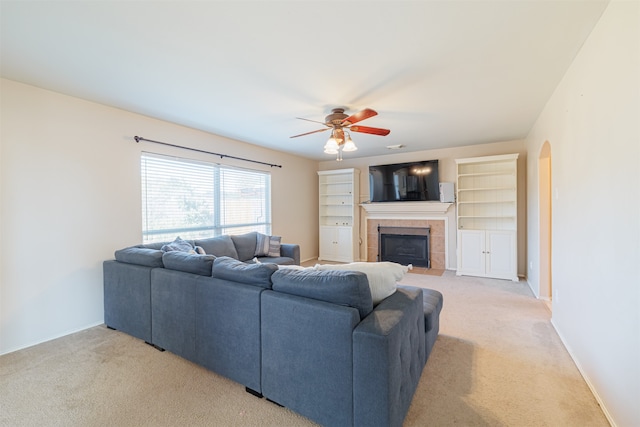 living room with light carpet, ceiling fan, and a tile fireplace