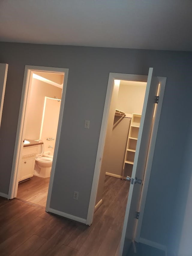 bedroom with a spacious closet, connected bathroom, a closet, and dark hardwood / wood-style floors