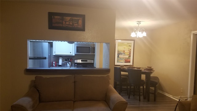 kitchen featuring pendant lighting, sink, a chandelier, appliances with stainless steel finishes, and hardwood / wood-style floors