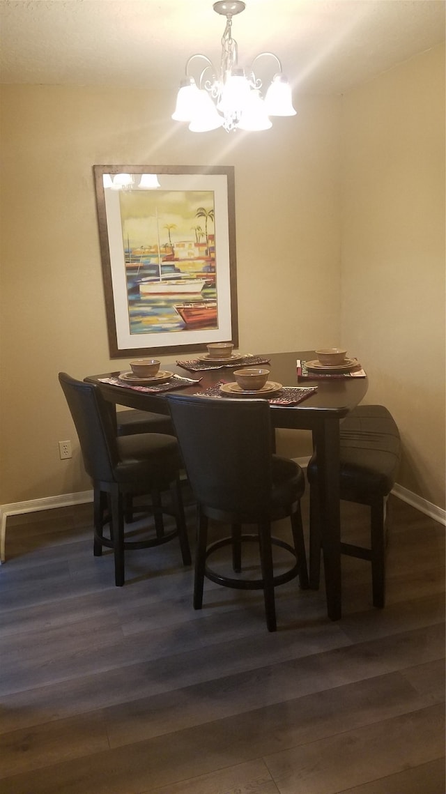 dining room with dark wood-type flooring and a chandelier