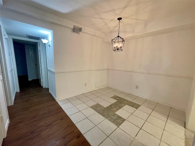 empty room with visible vents, baseboards, an inviting chandelier, and light wood-style flooring