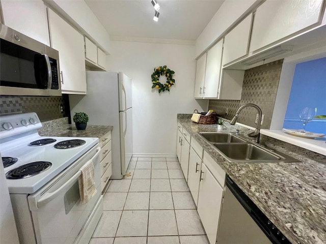 kitchen with appliances with stainless steel finishes, light tile patterned floors, white cabinets, decorative backsplash, and a sink