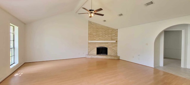 unfurnished living room with a brick fireplace, light hardwood / wood-style flooring, high vaulted ceiling, and ceiling fan