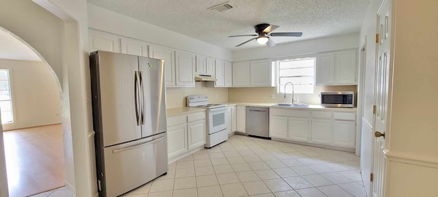 kitchen featuring sink, light tile patterned floors, stainless steel appliances, and white cabinets