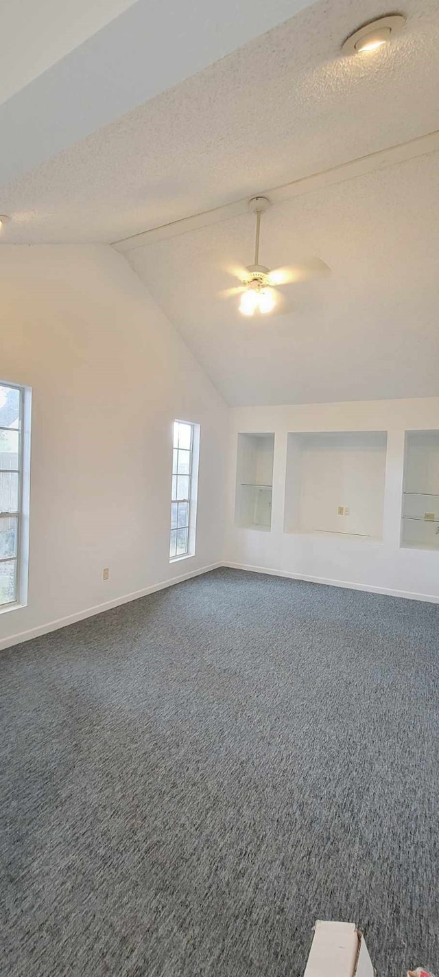 spare room featuring a textured ceiling, carpet, vaulted ceiling, and ceiling fan