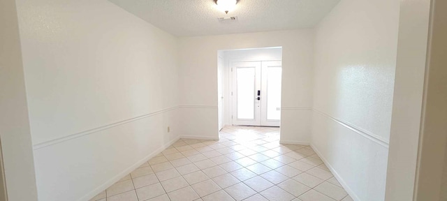 unfurnished room with french doors, light tile patterned flooring, and a textured ceiling