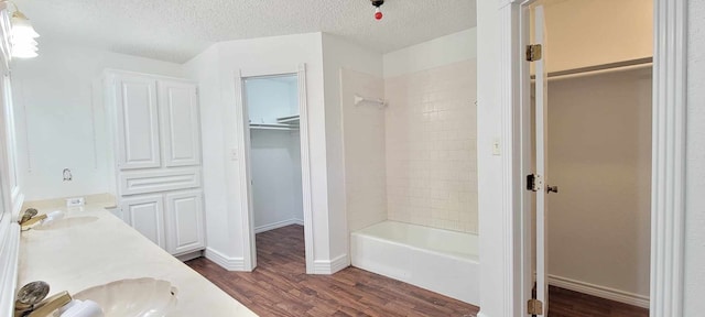 bathroom with a textured ceiling, tiled shower / bath combo, vanity, and hardwood / wood-style floors