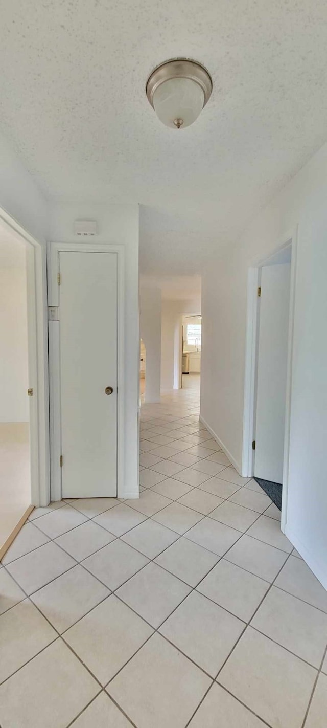 corridor featuring a textured ceiling and light tile patterned floors