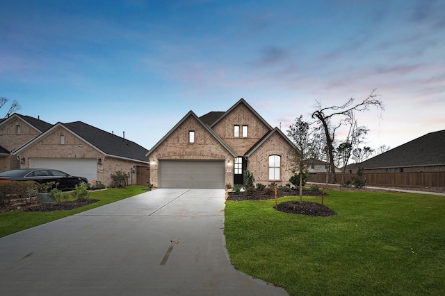 view of front of house with driveway, brick siding, fence, and a yard