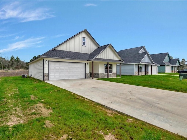 view of front of home with a garage, stone siding, concrete driveway, board and batten siding, and a front yard