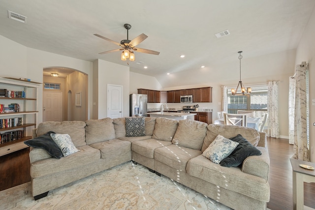 living room featuring vaulted ceiling, sink, ceiling fan with notable chandelier, and light hardwood / wood-style floors