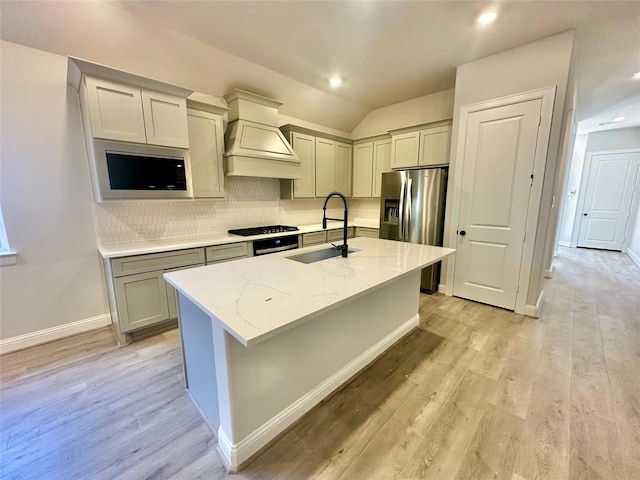 kitchen with stainless steel refrigerator with ice dispenser, sink, backsplash, premium range hood, and light stone counters