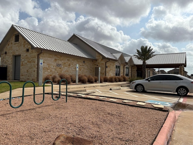 331 W Bend Dr, League City, TX 77573 - view of front facade with stone siding, uncovered parking, a standing seam roof, and a metal roof
