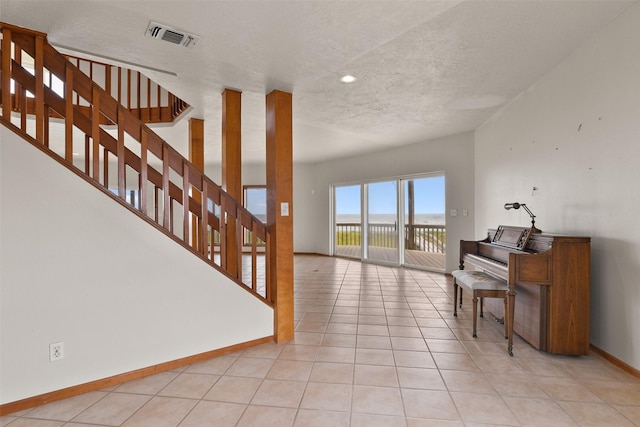 interior space with stairs, baseboards, a textured ceiling, tile patterned floors, and visible vents