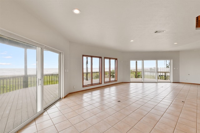 spare room featuring light tile patterned flooring and a water view