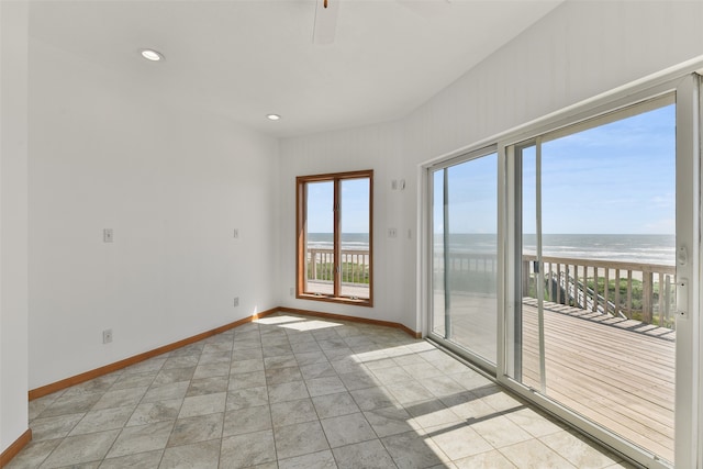 empty room featuring a view of the beach, a water view, and ceiling fan