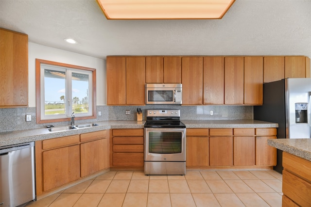 kitchen featuring appliances with stainless steel finishes, decorative backsplash, light tile patterned flooring, a textured ceiling, and sink