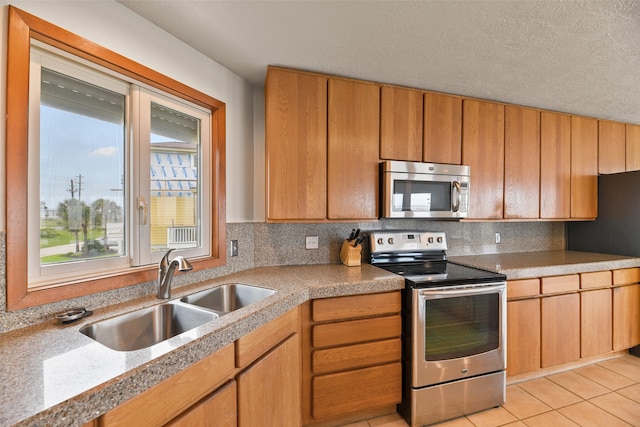 kitchen with tasteful backsplash, light tile patterned floors, stainless steel appliances, a textured ceiling, and sink