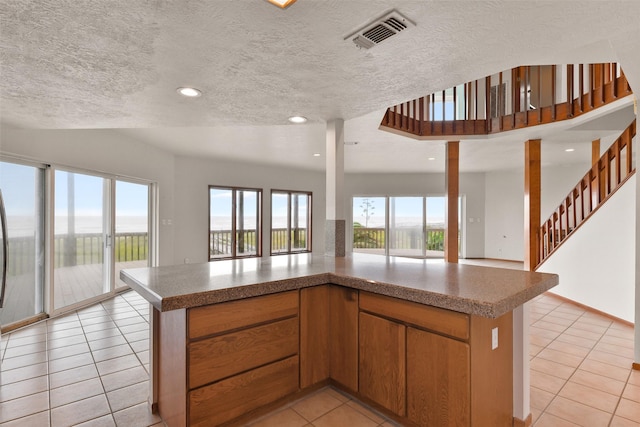 kitchen featuring a textured ceiling, visible vents, recessed lighting, open floor plan, and light tile patterned floors