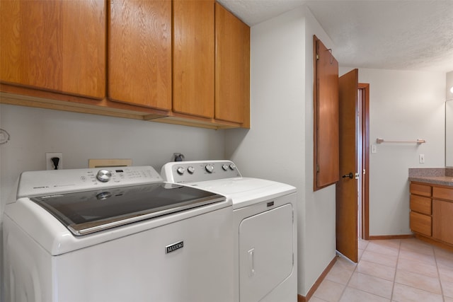 laundry room with cabinets, a textured ceiling, light tile patterned floors, and washing machine and dryer