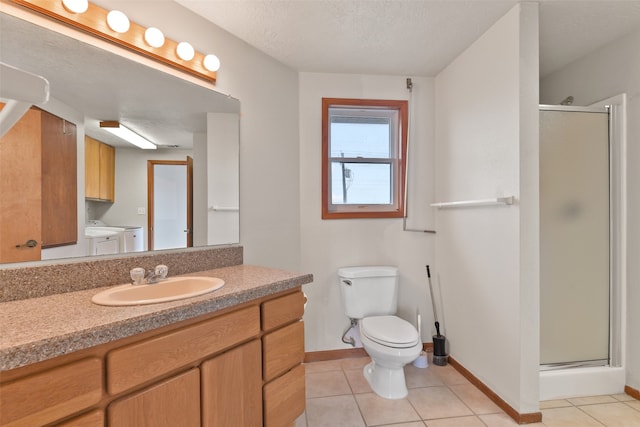 bathroom with vanity, toilet, washer and dryer, and a shower with door