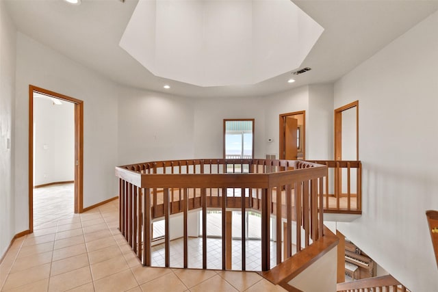 hallway with an upstairs landing, visible vents, baseboards, recessed lighting, and light tile patterned floors