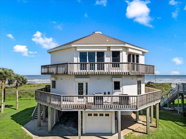 rear view of property featuring a balcony, a lawn, an attached garage, and stairway