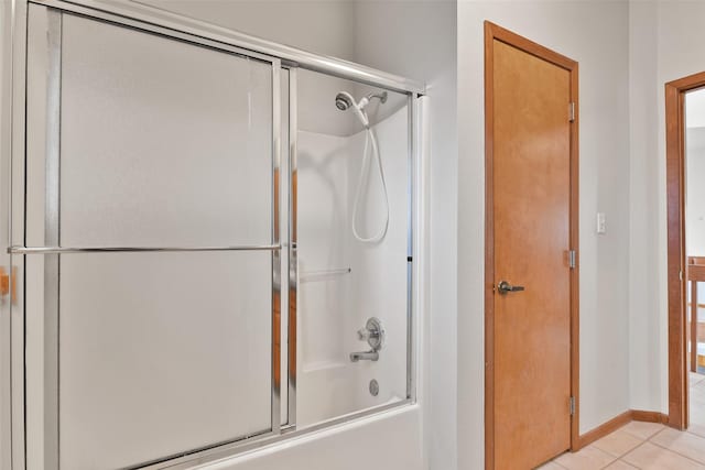 bathroom featuring tile patterned flooring, shower / bath combination with glass door, and baseboards