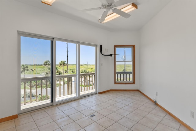 unfurnished room with light tile patterned flooring, baseboards, and a ceiling fan