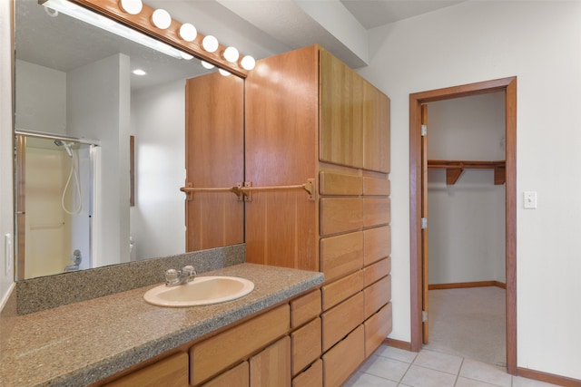 bathroom featuring tile patterned floors, a shower with door, and vanity