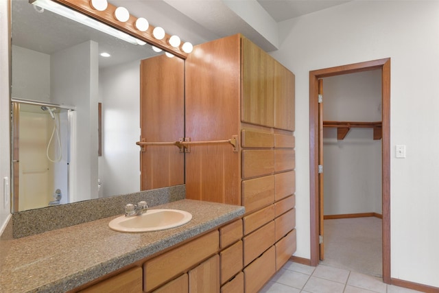 full bath with a shower with door, baseboards, tile patterned floors, and vanity