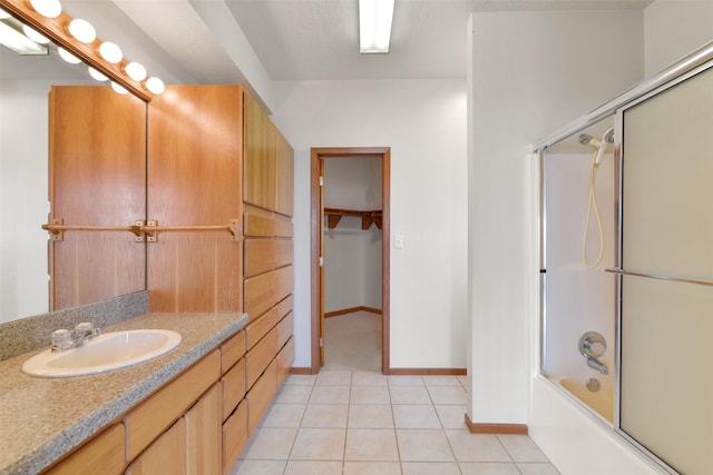 full bathroom featuring vanity, a spacious closet, bath / shower combo with glass door, tile patterned flooring, and baseboards