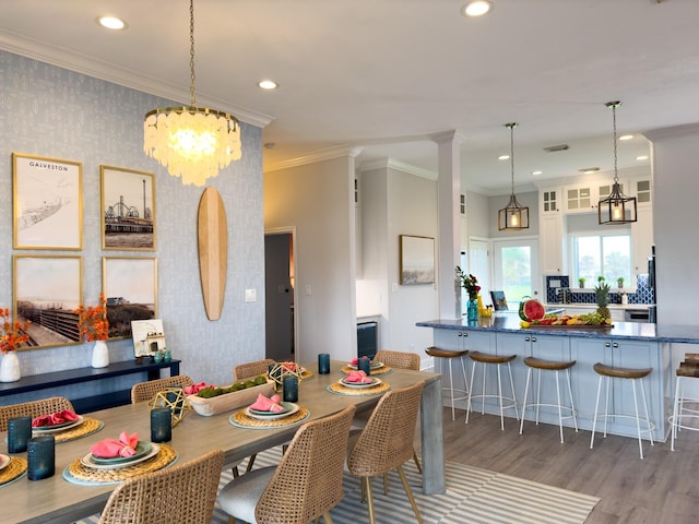 dining area with light wood finished floors, ornamental molding, recessed lighting, wallpapered walls, and a chandelier